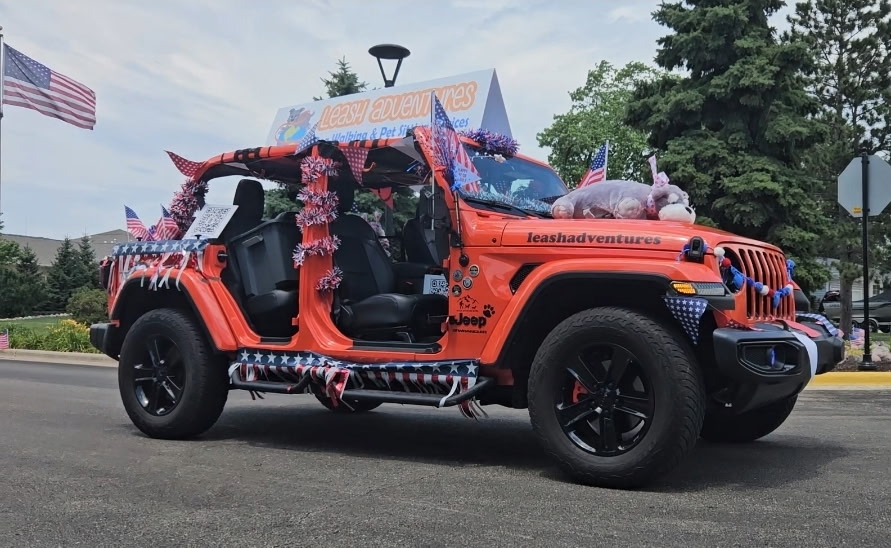 Leash Adventures orange Jeep decorated with American flags and stars for the 4th of July parade in Elmhurst, IL
